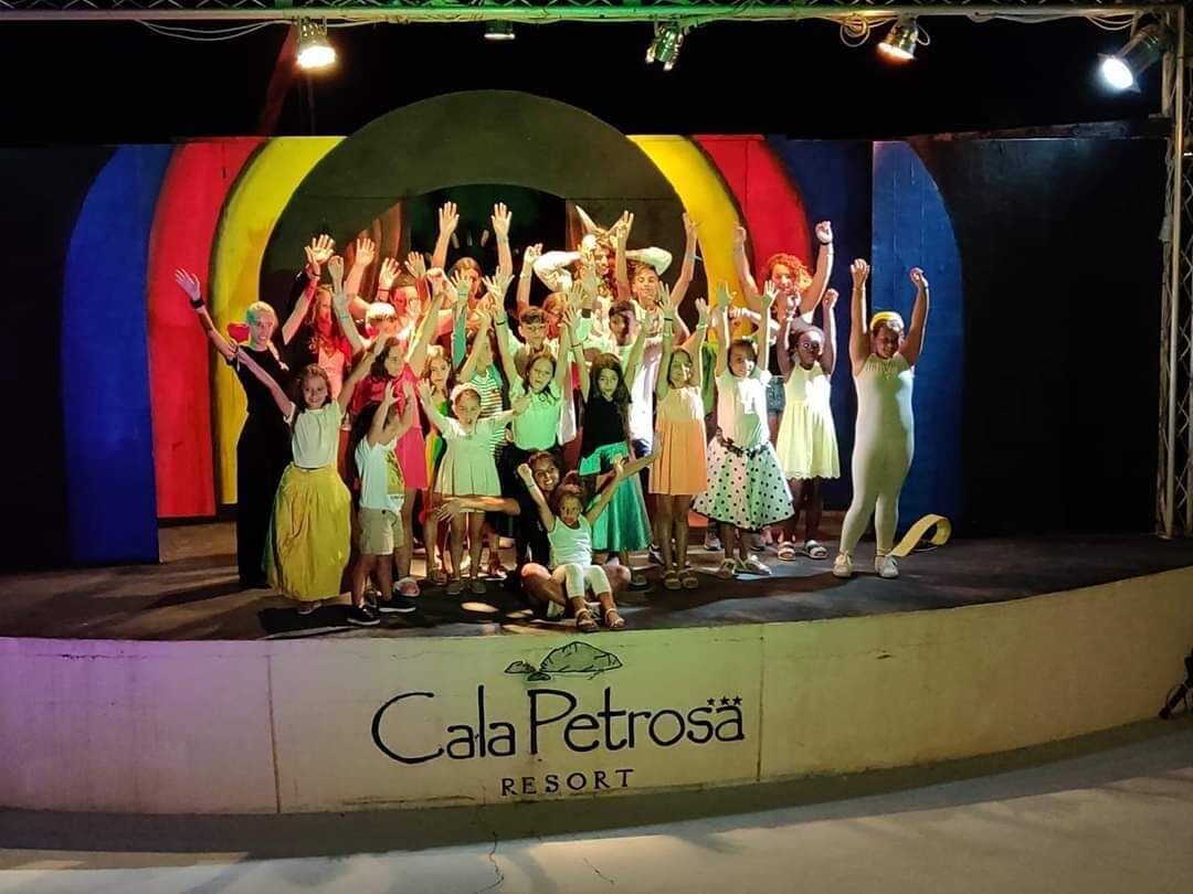A group of people on a stage with a colorful backdrop and the text "Cala Petrosa RESORT" at the bottom.
