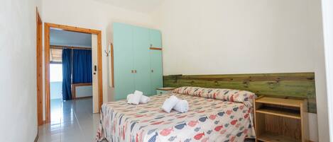 A bedroom with a bed, a wooden headboard, a nightstand, and a wardrobe.