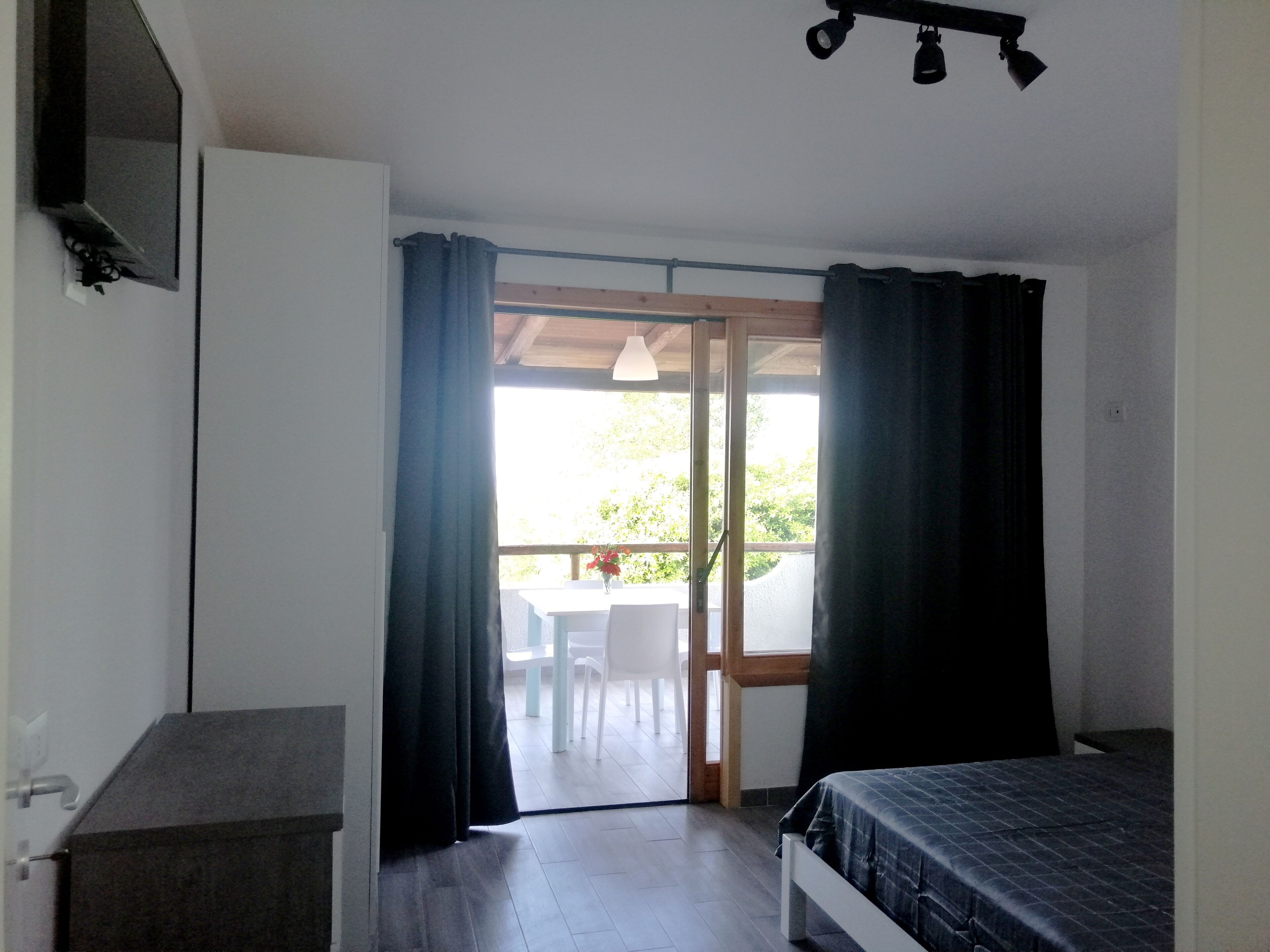A bedroom with a bed, a desk, and a window with curtains.