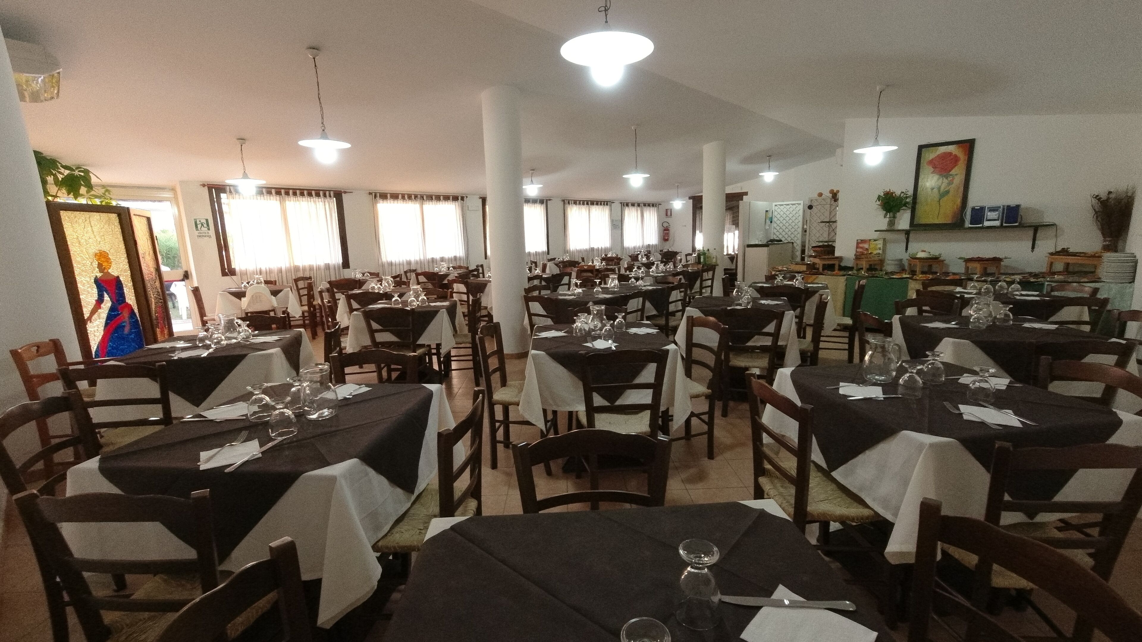 Un ristorante con diversi tavoli, sedie e lampade a sospensione.
