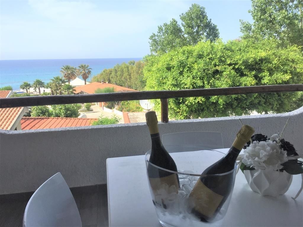 Un balcón con una mesa, dos botellas de champán y un florero con flores.