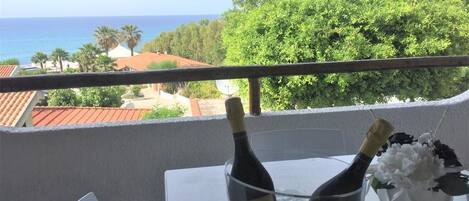 Un balcón con una mesa, dos botellas de champán y un florero con flores.