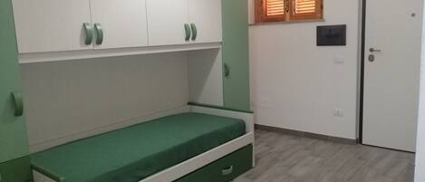 A room with a bed, a wardrobe, a window, and a door.