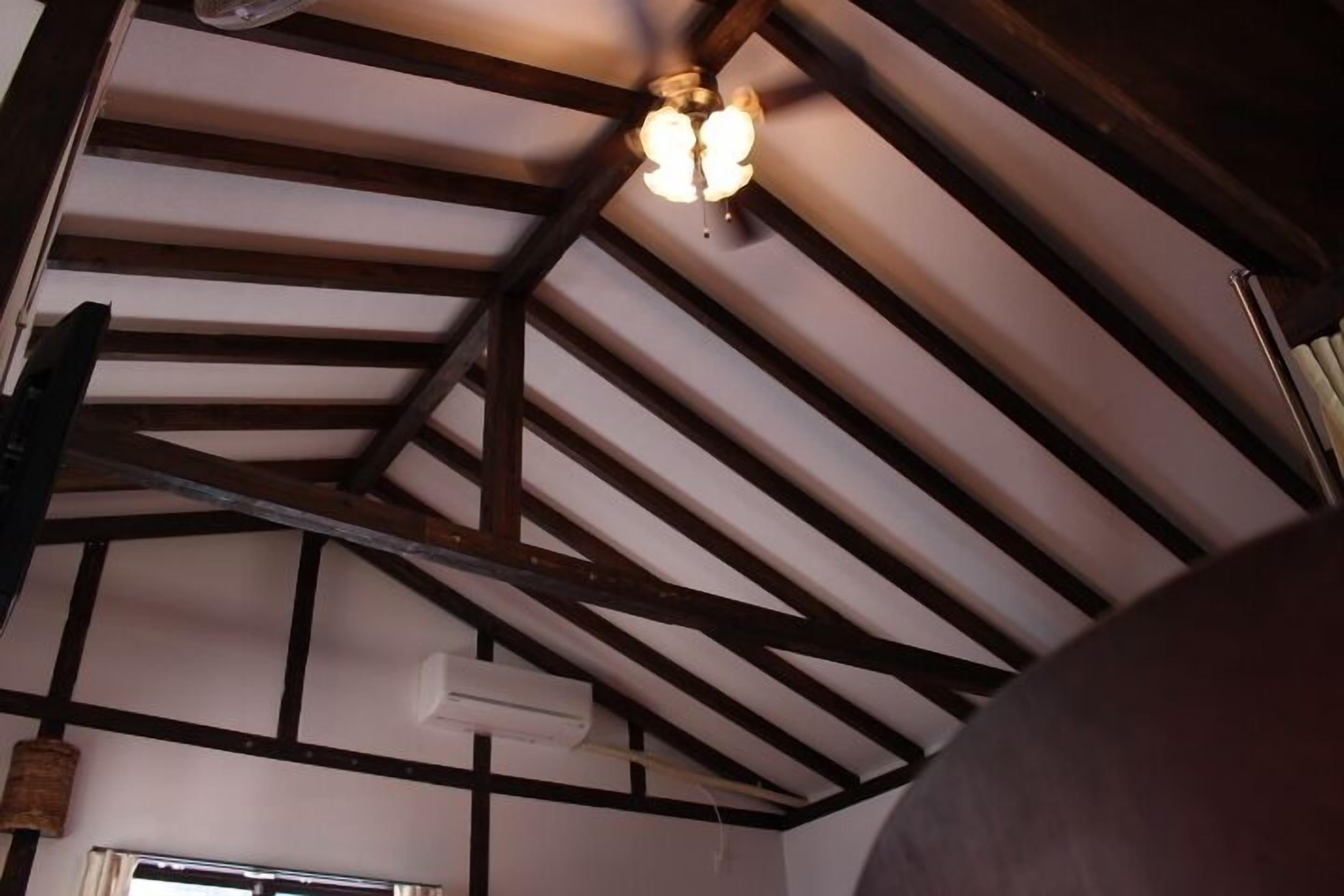 Une pièce avec des poutres apparentes, un ventilateur de plafond et un appareil de climatisation.