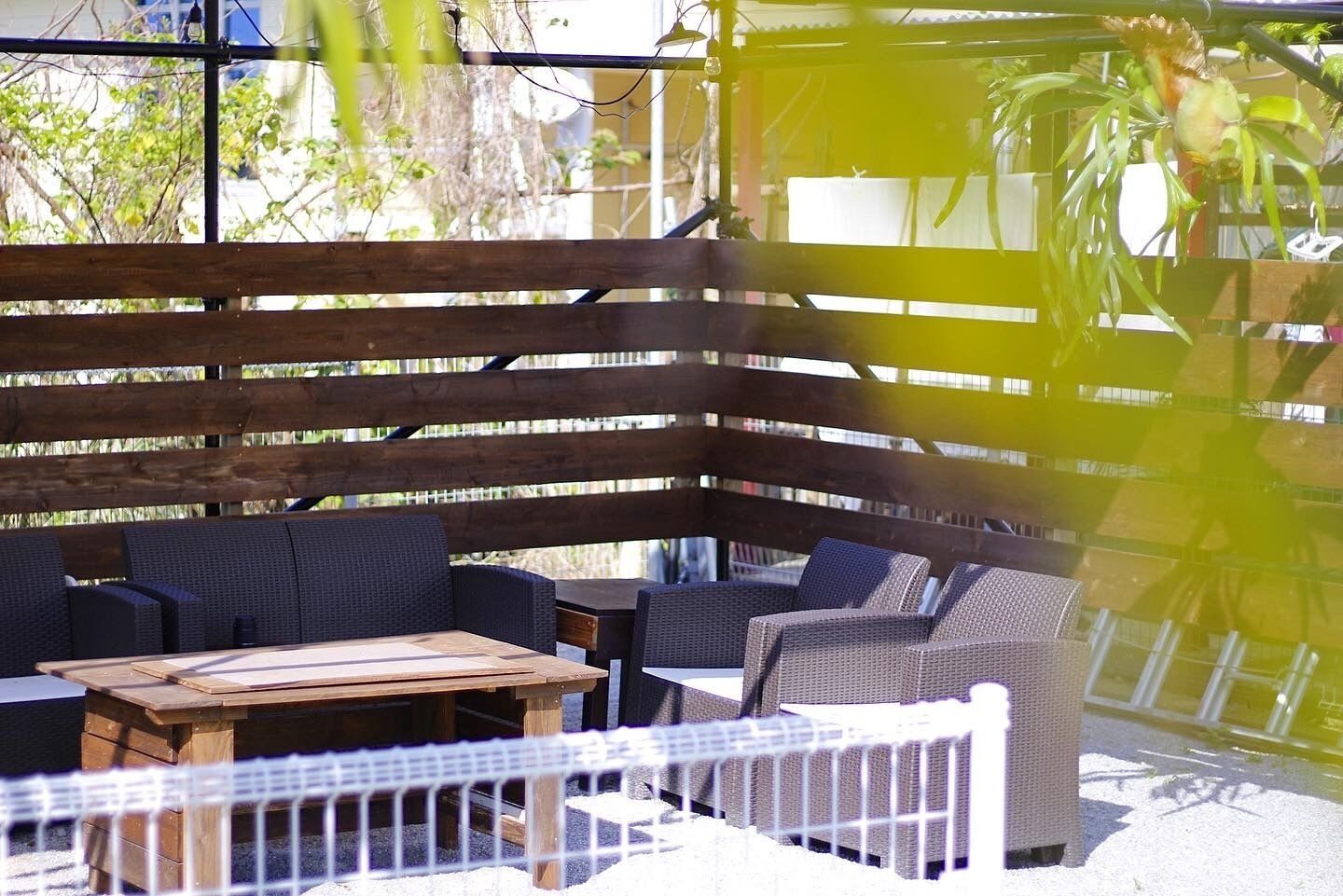An outdoor patio area with wicker furniture and a wooden table.