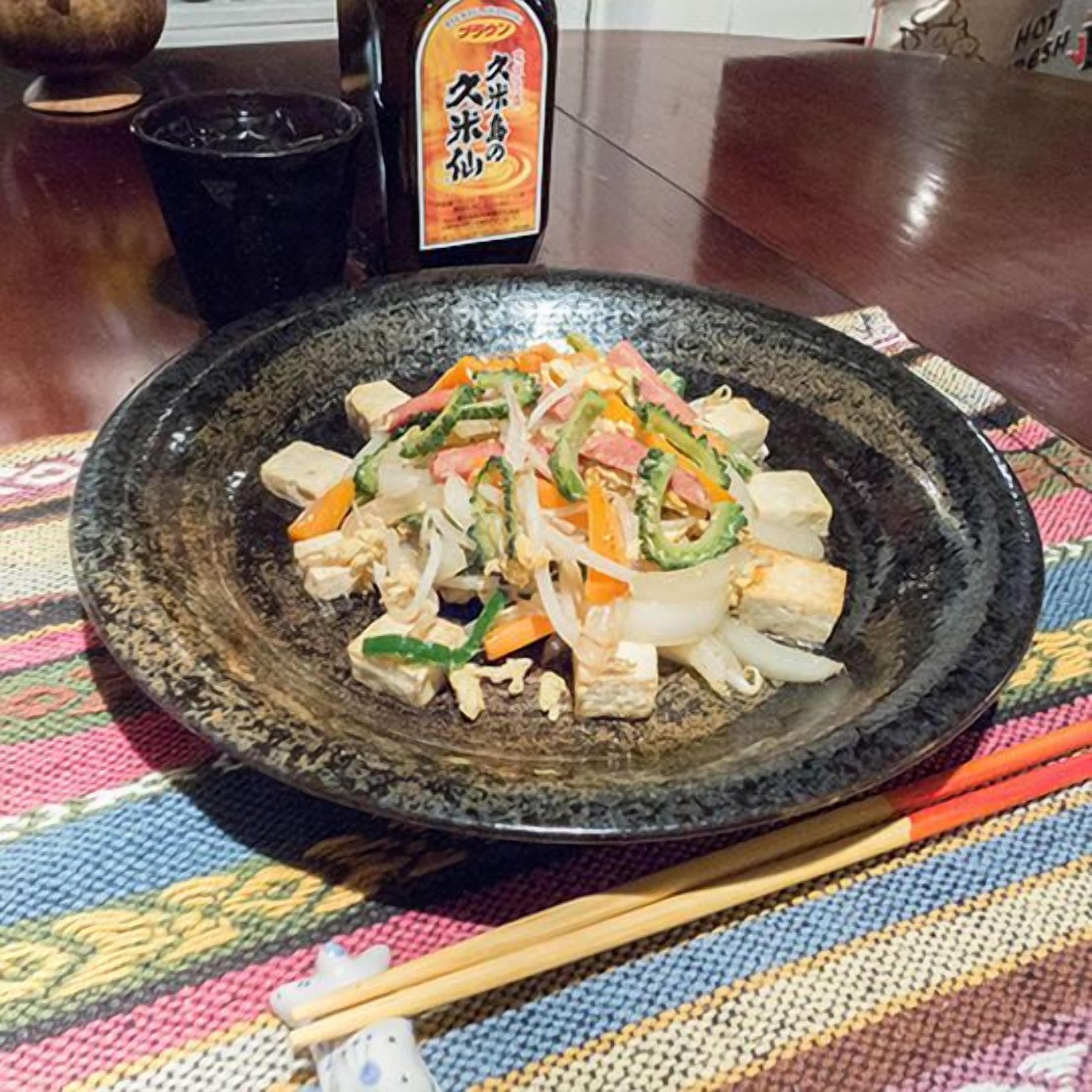 A plate of stir-fried vegetables and tofu on a textured tablecloth.