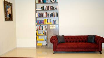 A red sofa, a bookshelf, and a framed picture on a wall.