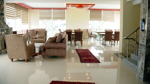 A spacious living area with a stone fireplace, comfortable seating, and a staircase leading to an upper level. - Tehran Boutique Hotel (Dogubayazit)