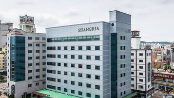 A multi-story building with a modern design, labeled "SHANGRIA." It features a green roof and is surrounded by a cityscape.