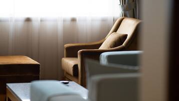 Una habitación con un sillón de cuero marrón, una pequeña mesa de madera y un sofá blanco.