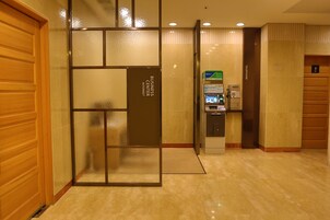 Vestíbulo de hotel con recepción, centro de negocios y cabina telefónica.