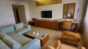 A modern living room with a sofa, armchairs, a coffee table, a TV, and a desk with a mirror.