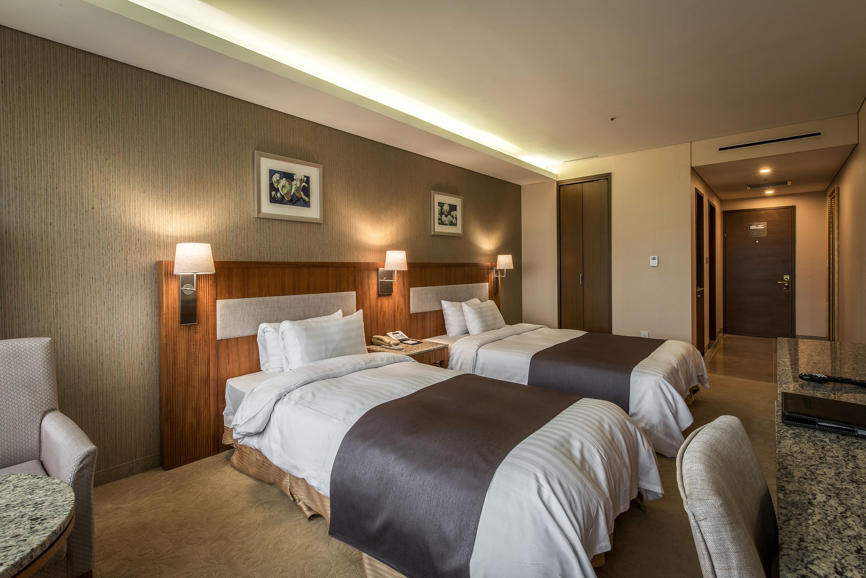 Ett hotellrum med två sängar, ett skrivbord, en stol och ett litet bord.