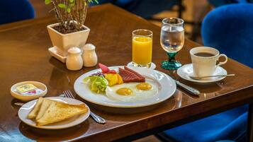 A breakfast setting with toast, eggs, and juice on a wooden table.