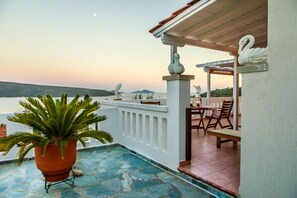 A terrace with a potted plant, outdoor seating, and a view of the sea. - Anatoli Villa (Alonissos)