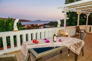 A terrace with a table set for two, overlooking a coastal view. - Anatoli Villa (Alonissos)