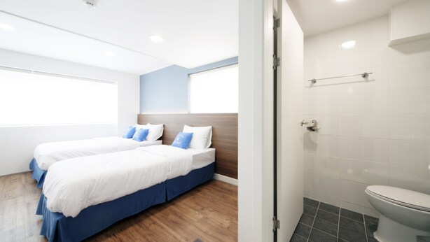 A modern hotel room with two beds, a bathroom, and a view of the outside. - K-Guesthouse Seomyeon 1 (Busan)