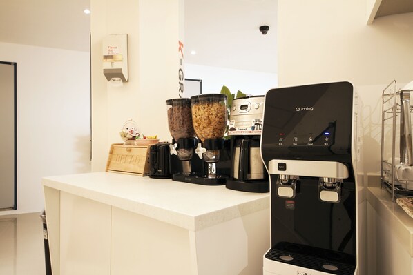 Una estación de café moderna con una máquina de café Quming, dos molinillos y un dispensador de pañuelos.