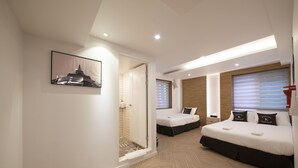 A modern hotel room with a large bed, a smaller bed, a shower area, and a framed picture on the wall. - K-Guesthouse Seomyeon 1 (Busan)