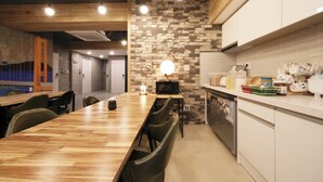 A modern kitchen with a wooden table and chairs, a brick wall, and white cabinets.