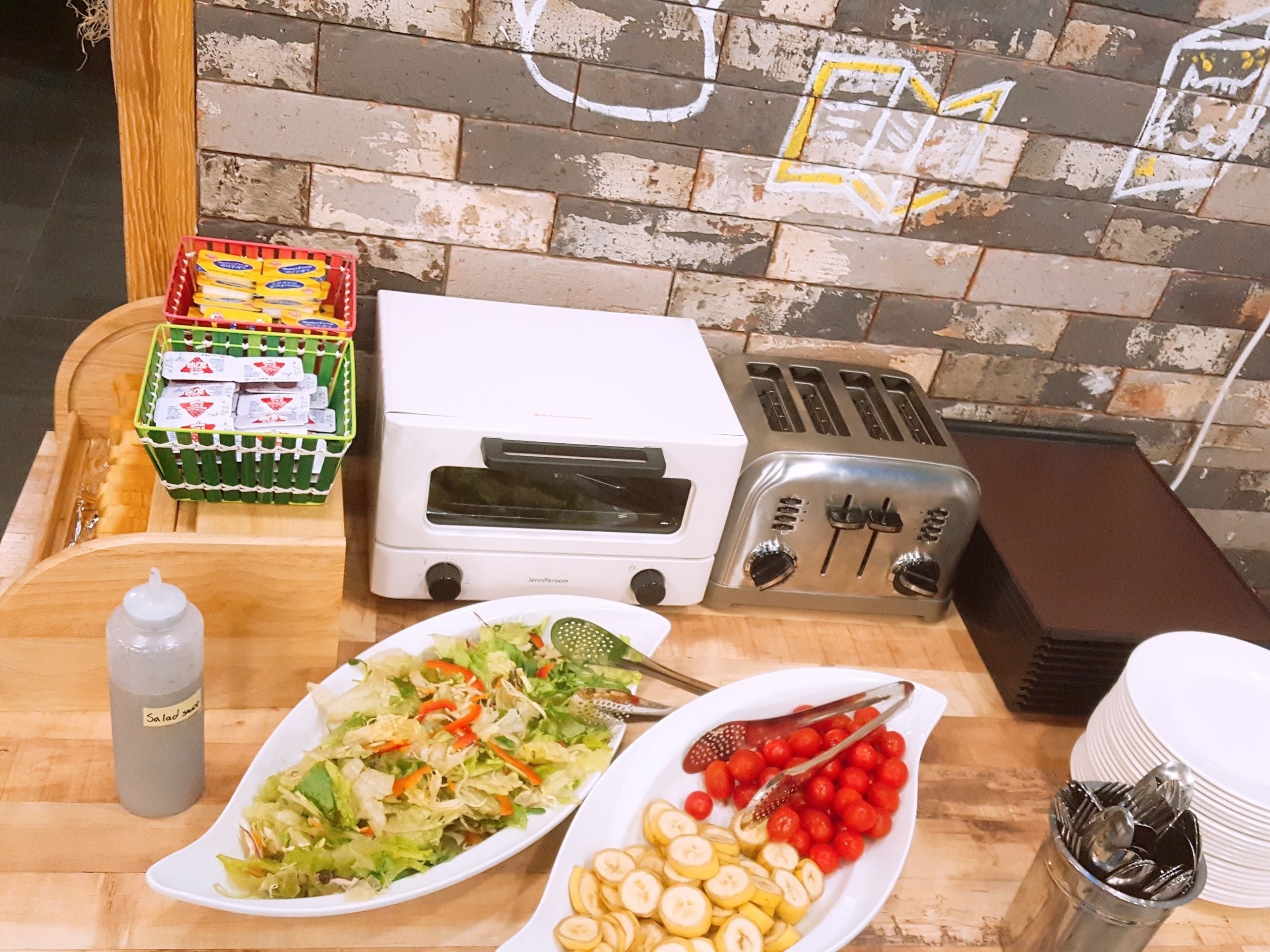 Una encimera de cocina con un tostador, una ensalada y un plato de rodajas de plátano.