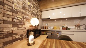 A kitchen with wooden brick walls, a wooden table, and white cabinets.