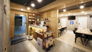 A modern guesthouse interior with a reception desk, wooden walls, and a dining area.