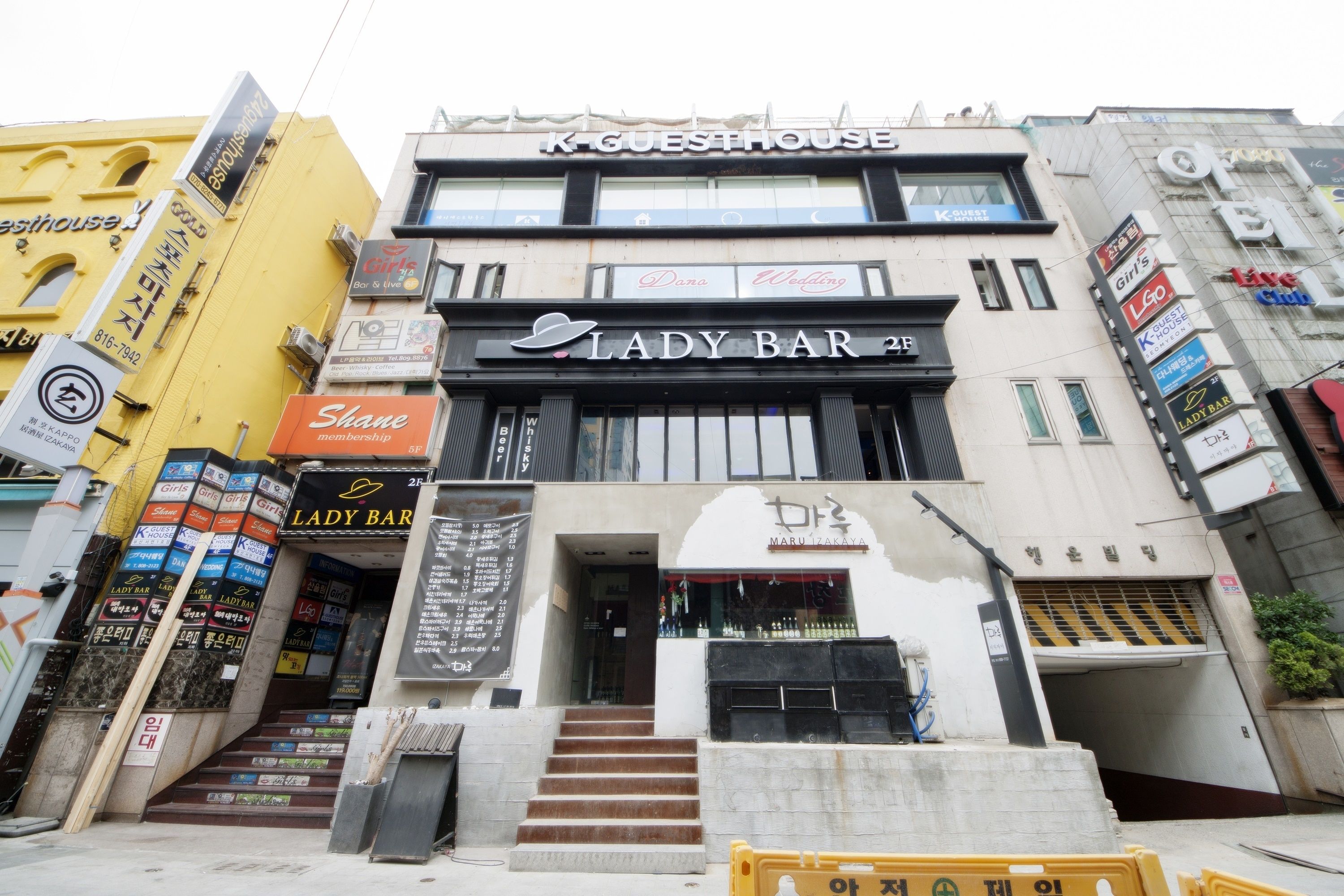 A multi-story building with various businesses including a Lady Bar and a K-GUESTHOUSE.