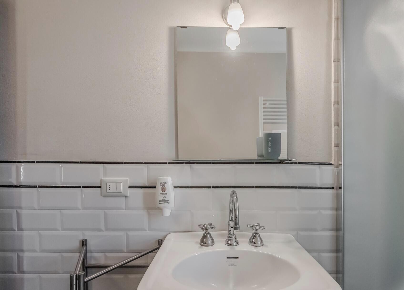 A bathroom with a white sink, a mirror, and a towel rack.