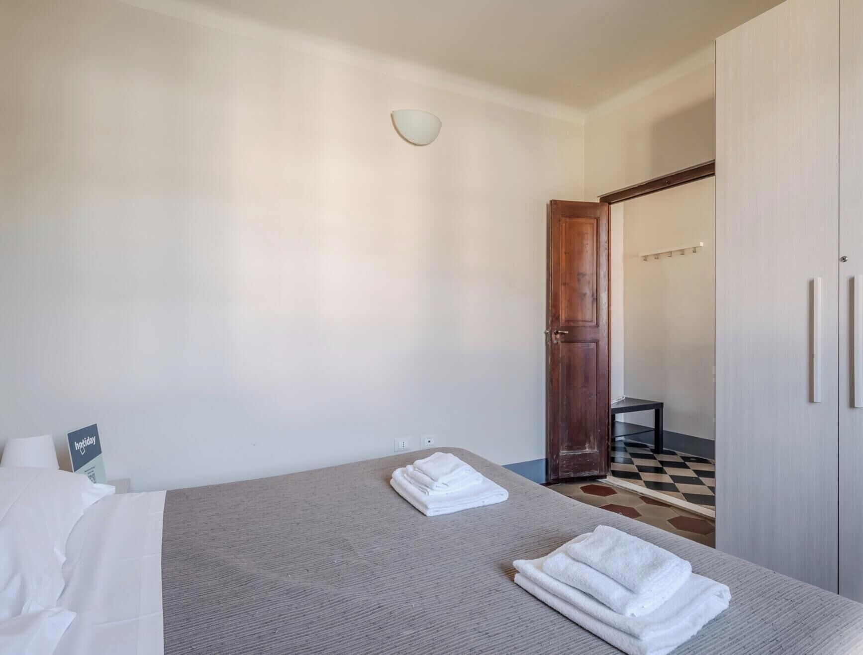 Ein Hotelzimmer mit einem Bett, einem Nachttisch, einem Kleiderschrank und einem Schachbrettmuster-Boden.