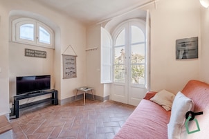 Una sala de estar con televisor, una mesita, un sofá y una puerta que da al exterior.
