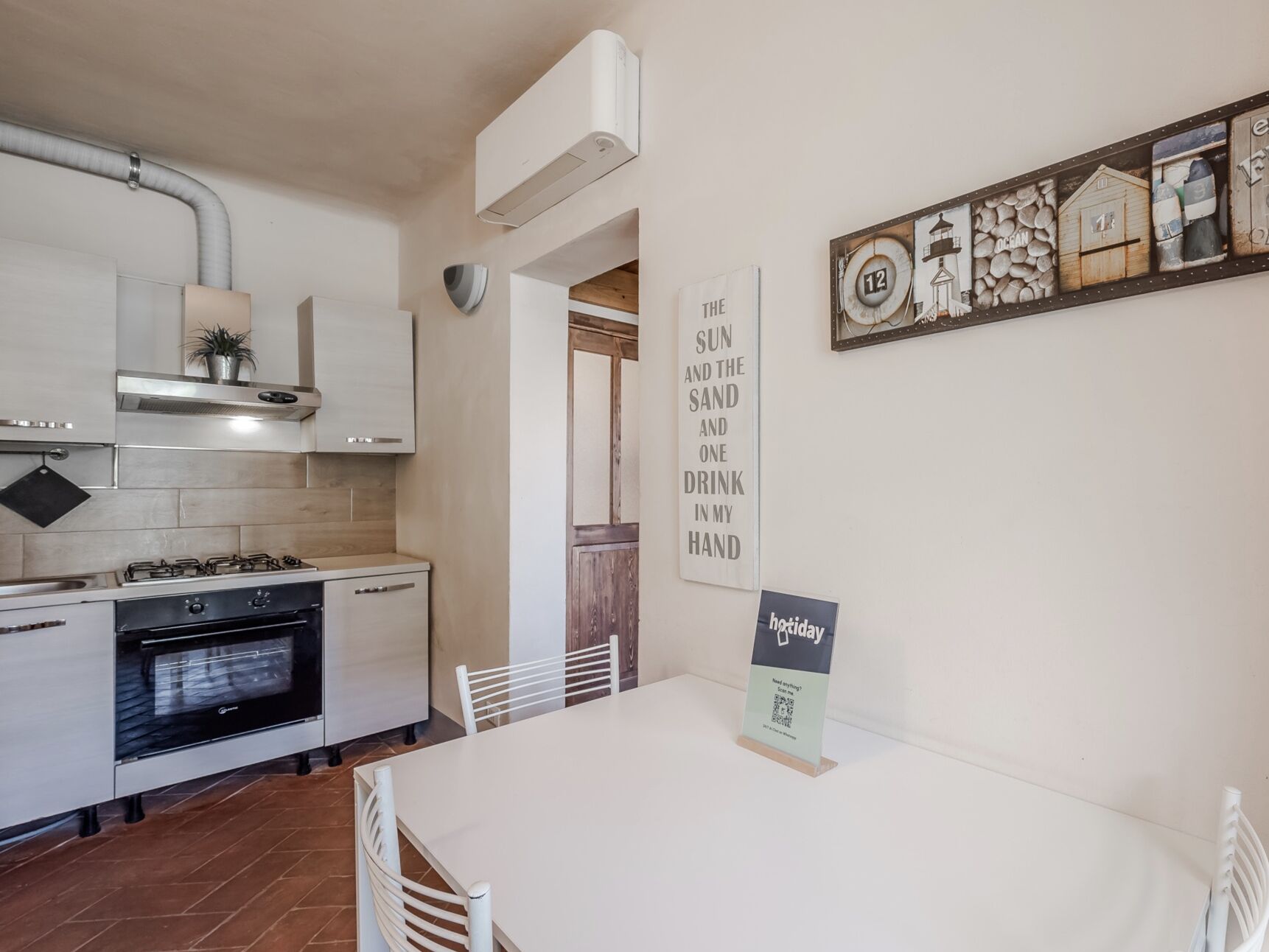 A modern kitchen with white cabinets, a stove, and an oven. There is a dining table with chairs and a sign on it.