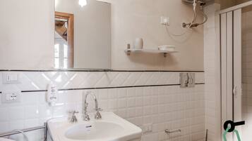 A bathroom with a sink, mirror, and shower.