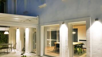 A modern house with a covered patio, large windows, and potted plants.