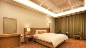 Habitación de hotel con una cama grande, una mesita de noche, una lámpara, una silla y un espejo.