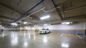 Un aparcamiento interior espacioso con un coche blanco estacionado en una de las plazas.