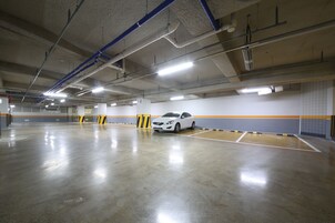Garagem de estacionamento coberta espaçosa, com um carro branco estacionado numa das vagas.