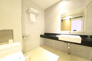 Ein modernes Badezimmer mit einem weißen Waschbecken, einer schwarzen Arbeitsplatte und einem Spiegel darüber.