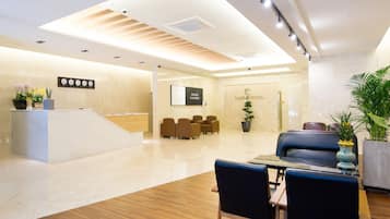 A hotel reception area with a modern design, including a reception desk, seating area, and a sign for the hotel.