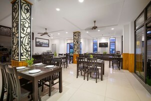 Un comedor amplio con varias mesas y sillas, una zona de bar y un televisor montado en la pared.