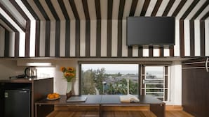 A modern kitchen with a large window, a flat-screen TV, and a dining area with a bench and cushions. - Stayzi Hotel (Da Nang)