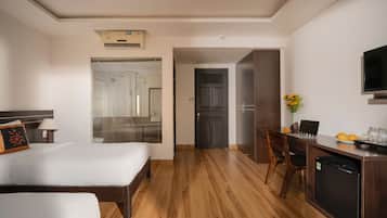 Habitación de hotel con dos camas, un escritorio con una computadora portátil, un televisor y zona de ducha.