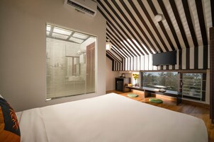 Un dormitorio moderno con una cama grande, un televisor montado en la pared y una ventana con persianas.