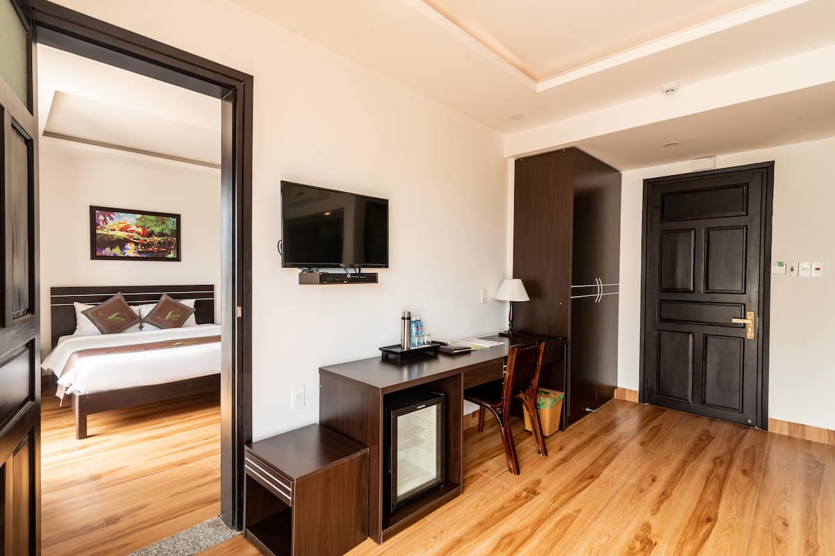 A hotel room with a bed, a desk with a computer, a television, and a door.
