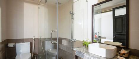 A modern bathroom with a glass-enclosed shower, a toilet, and a sink with a large mirror.