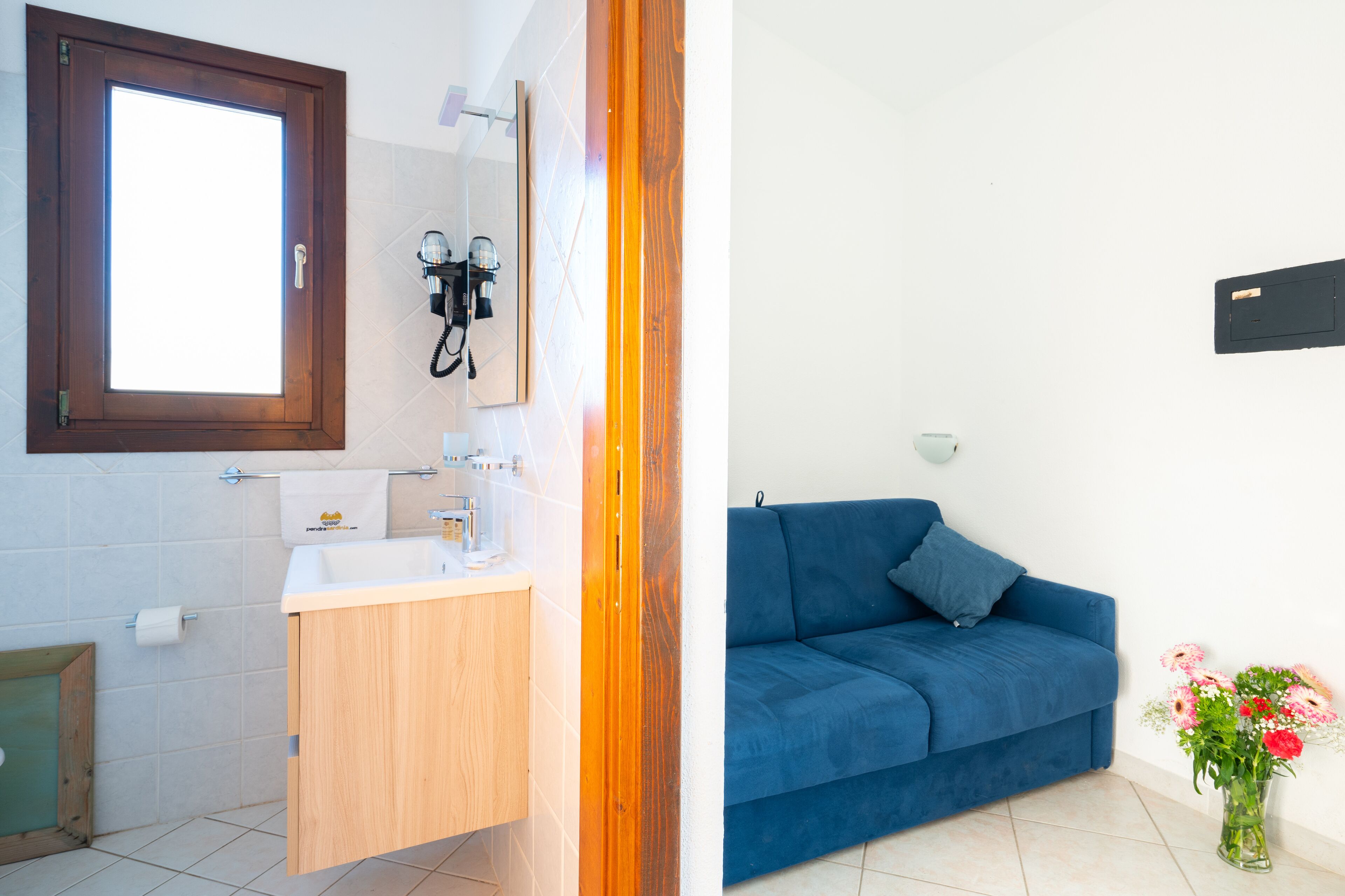 Une salle de bain avec un meuble-lavabo en bois, un miroir et une serviette accrochée au mur.