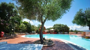 A swimming pool with lounge chairs and a tree in the center. - Residence Costa del Turchese by PendraHolidays (Badesi)
