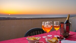 A table set with glasses of wine, a bottle of champagne, and snacks by a beach at sunset. - Residence Costa del Turchese by PendraHolidays (Badesi)