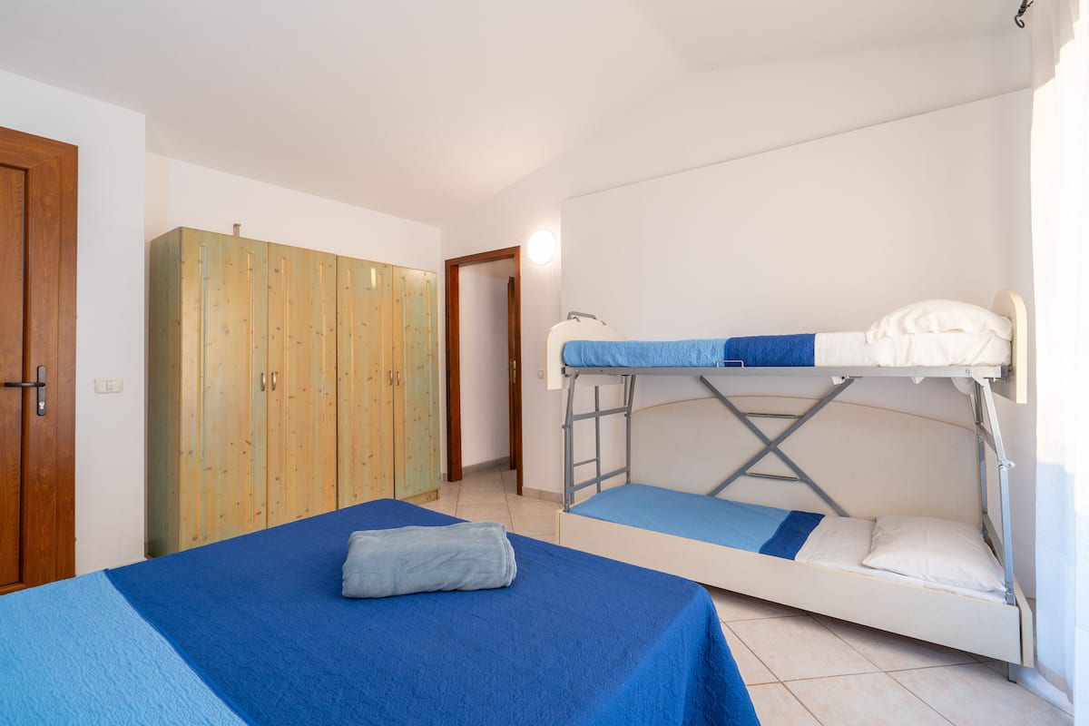 Ein Zimmer mit zwei Betten, darunter einem Etagenbett, einem Holzschrank und einer Tür.