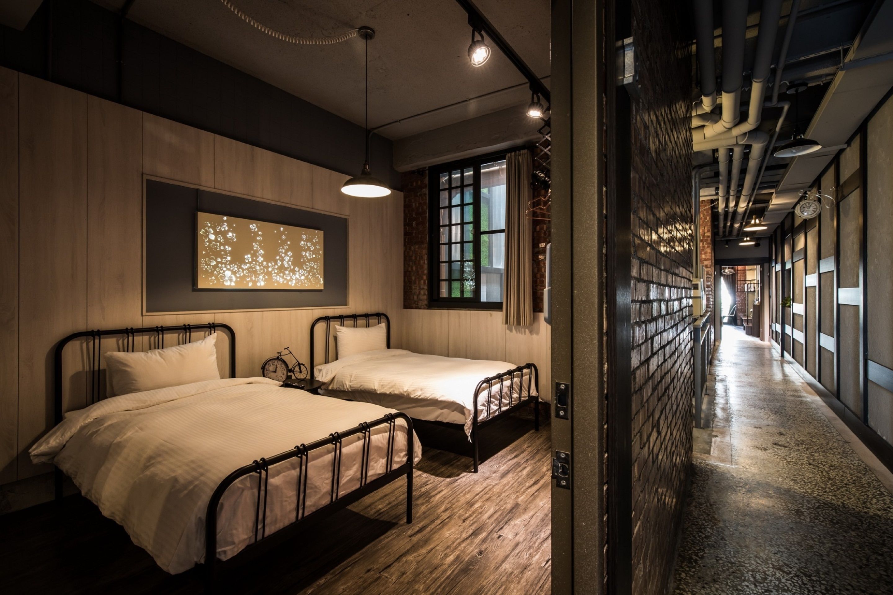Une chambre d’hôtel avec deux lits, un plancher en bois, une grande fenêtre et une œuvre d’art accrochée au mur.